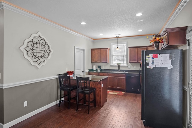 kitchen featuring dark countertops, dark wood-style floors, hanging light fixtures, black appliances, and a sink