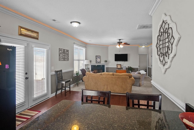 living room featuring visible vents, baseboards, dark wood-style floors, ceiling fan, and ornamental molding