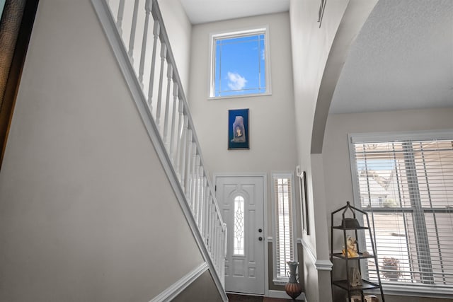 entryway featuring a high ceiling, stairs, and arched walkways