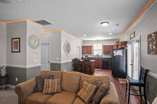 living area with visible vents, crown molding, a textured ceiling, and baseboards