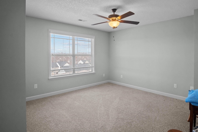 carpeted empty room with baseboards, visible vents, ceiling fan, and a textured ceiling