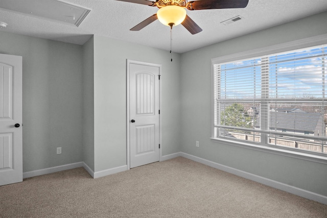 unfurnished bedroom featuring light carpet, a textured ceiling, visible vents, and baseboards