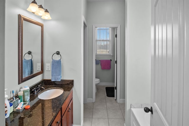 bathroom with a tub to relax in, baseboards, toilet, tile patterned floors, and vanity