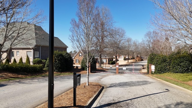 view of road with a residential view, a gate, a gated entry, and curbs