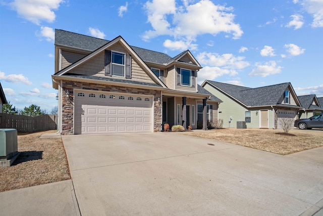 craftsman inspired home featuring central AC unit, fence, a garage, stone siding, and driveway