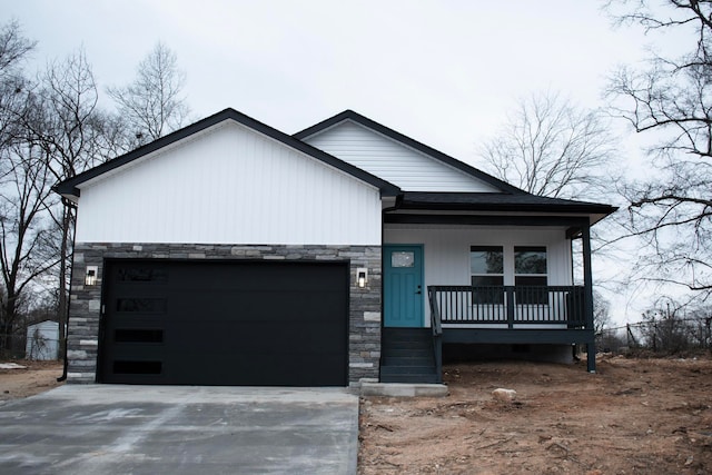 view of front of home with covered porch, stone siding, concrete driveway, and a garage