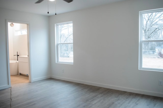 unfurnished bedroom featuring light wood-style floors, baseboards, and ensuite bathroom