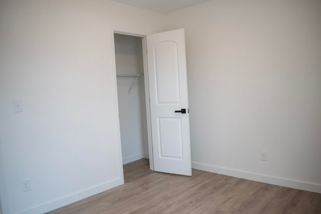 unfurnished bedroom featuring a closet, light wood-style flooring, and baseboards