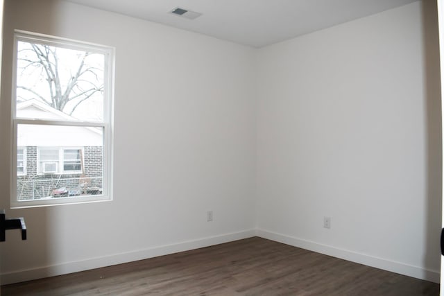 spare room featuring dark wood-style floors, a wealth of natural light, visible vents, and baseboards