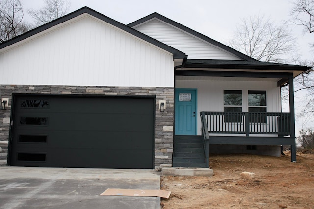 view of front of property with concrete driveway, stone siding, an attached garage, crawl space, and a porch