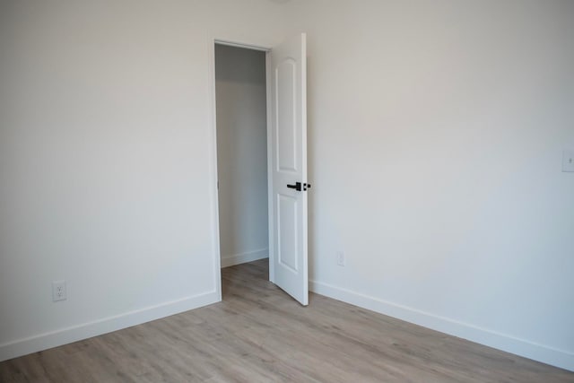 unfurnished room with light wood-style flooring and baseboards