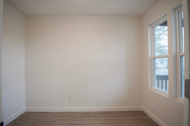 spare room featuring dark wood-style floors and baseboards