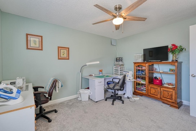 office area with a ceiling fan, baseboards, a textured ceiling, and light colored carpet