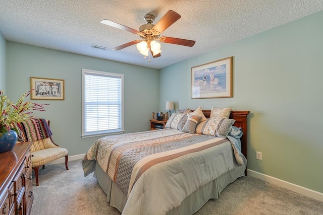 bedroom featuring light colored carpet, visible vents, a textured ceiling, and baseboards