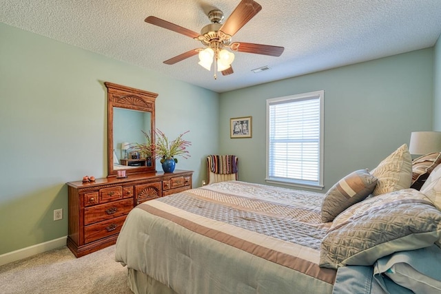 bedroom featuring a textured ceiling, baseboards, visible vents, and light colored carpet