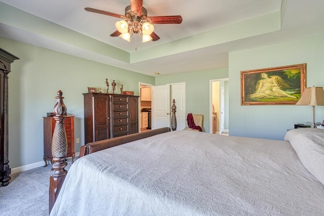 bedroom featuring a raised ceiling, a ceiling fan, light carpet, connected bathroom, and baseboards