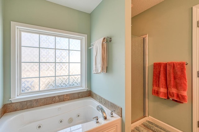 bathroom featuring a stall shower, a tub with jets, and a textured ceiling