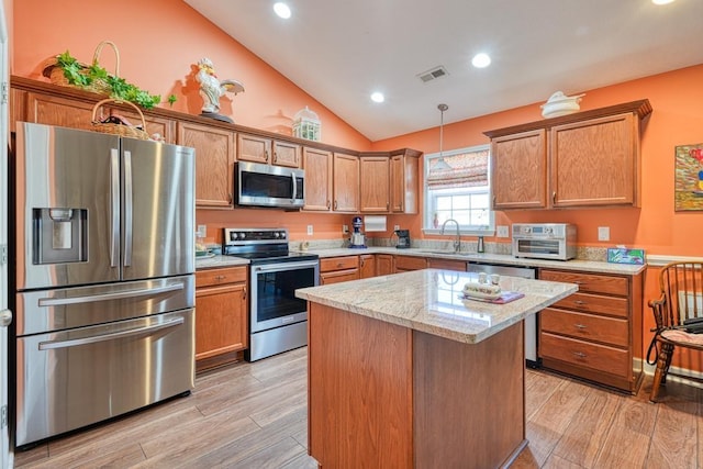 kitchen with light wood-style floors, a kitchen island, stainless steel appliances, and decorative light fixtures