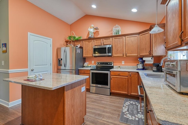 kitchen featuring stainless steel appliances, a center island, pendant lighting, and brown cabinetry