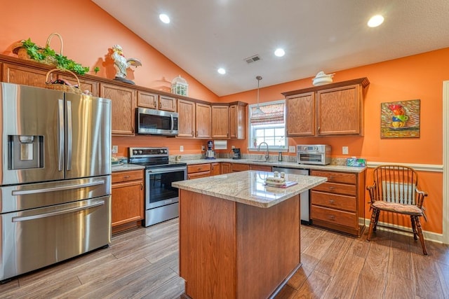 kitchen featuring a kitchen island, visible vents, appliances with stainless steel finishes, light wood finished floors, and decorative light fixtures