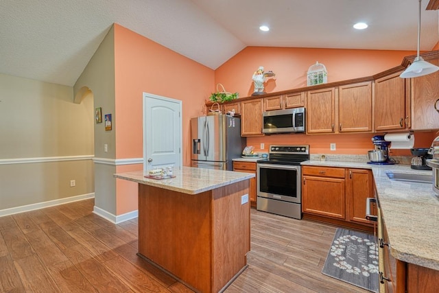 kitchen with hanging light fixtures, brown cabinets, stainless steel appliances, and a center island