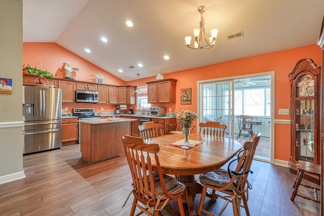 dining space with lofted ceiling, a textured ceiling, a notable chandelier, visible vents, and light wood-style floors