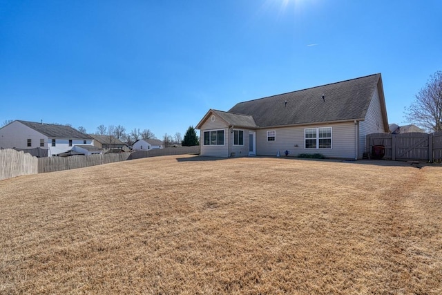 rear view of property with a lawn and a fenced backyard