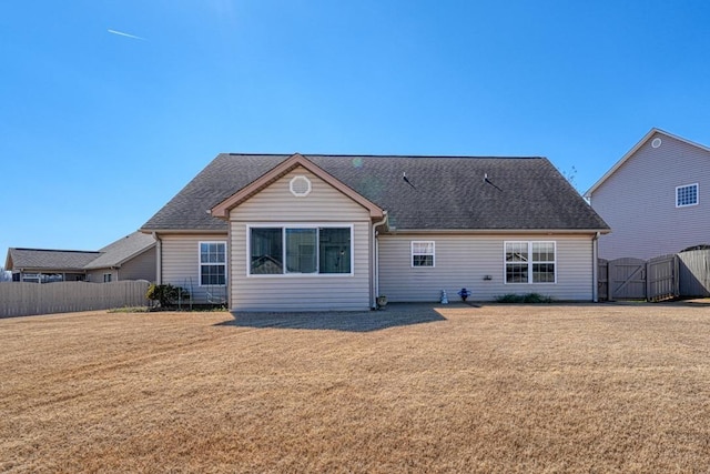 back of property featuring a gate, fence, a lawn, and roof with shingles