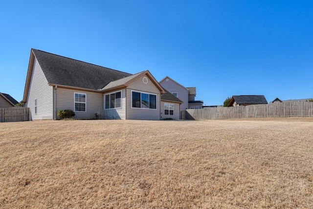 rear view of property featuring a yard and fence