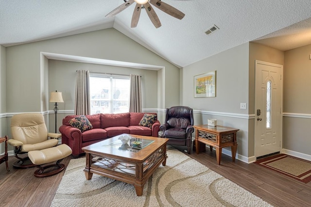 living area with visible vents, ceiling fan, dark wood-type flooring, vaulted ceiling, and a textured ceiling