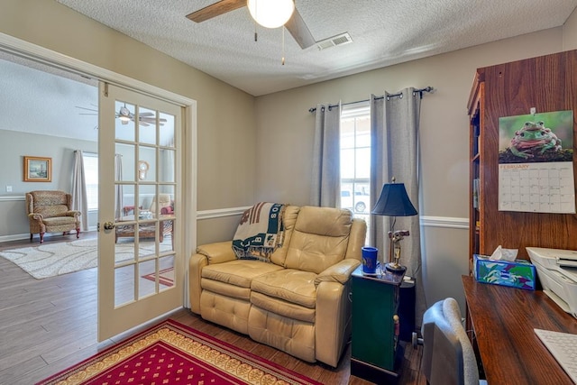 sitting room featuring visible vents, a textured ceiling, a ceiling fan, and wood finished floors