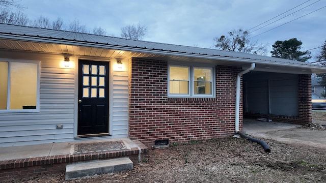 doorway to property featuring crawl space, metal roof, and brick siding