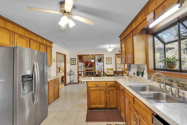 kitchen featuring light countertops, a peninsula, a sink, and stainless steel fridge with ice dispenser