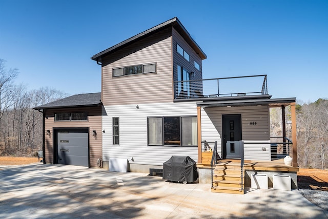 back of property featuring a garage, driveway, and a balcony