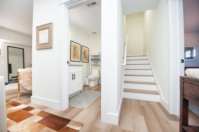 stairs featuring wood finished floors, visible vents, and baseboards