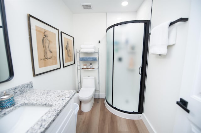 bathroom with a stall shower, visible vents, toilet, wood finished floors, and vanity