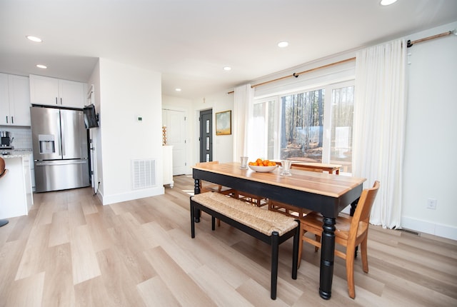 dining room with light wood-style floors, visible vents, and baseboards