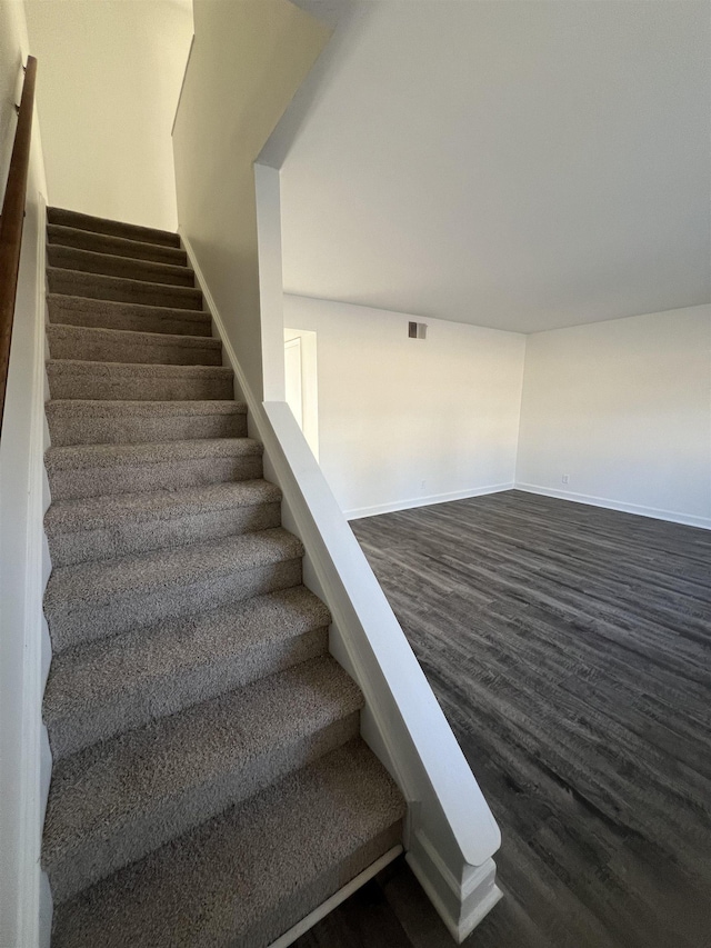 stairway with visible vents, baseboards, and wood finished floors