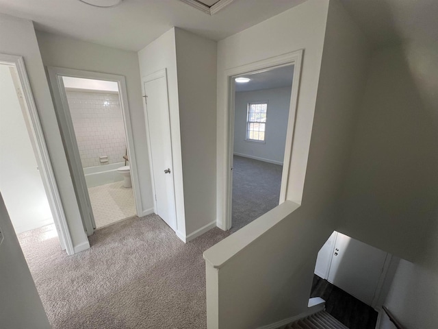 hallway featuring light carpet, an upstairs landing, and baseboards