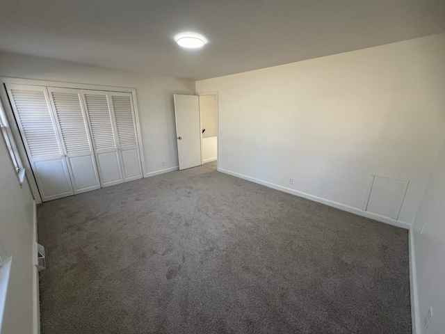 unfurnished bedroom featuring a closet, dark carpet, and baseboards