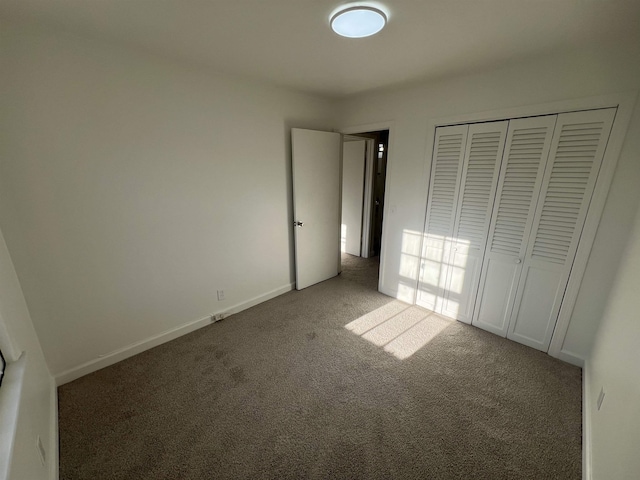 unfurnished bedroom with a closet, carpet flooring, and baseboards