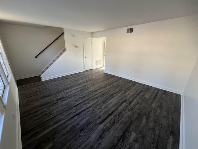 unfurnished room with dark wood-style floors, stairway, visible vents, and baseboards