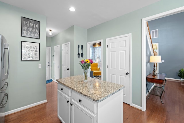 kitchen with visible vents, freestanding refrigerator, white cabinets, wood finished floors, and baseboards