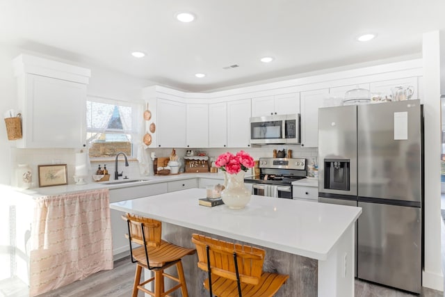 kitchen with stainless steel appliances, light countertops, a sink, and a breakfast bar area