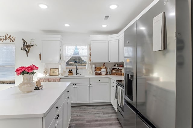 kitchen featuring tasteful backsplash, light countertops, appliances with stainless steel finishes, white cabinets, and a sink