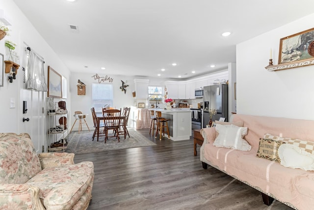 living area with dark wood-style flooring and recessed lighting