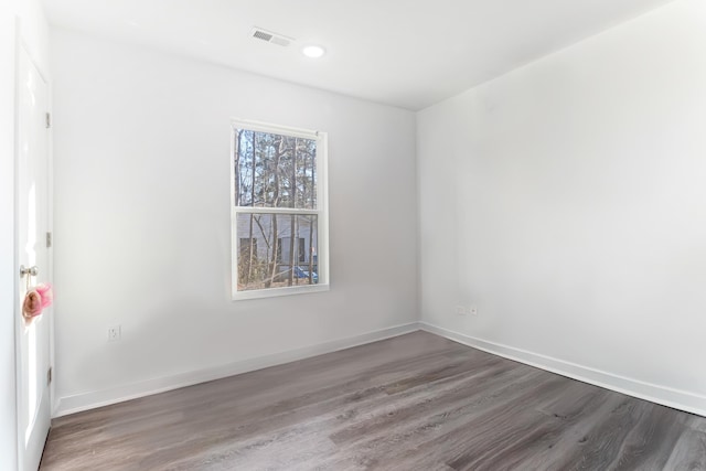 unfurnished room with dark wood-style floors, visible vents, and baseboards