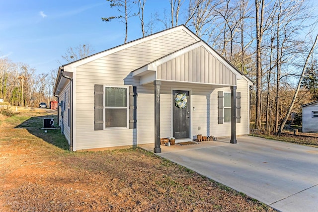 bungalow-style home with central AC, a front lawn, and board and batten siding