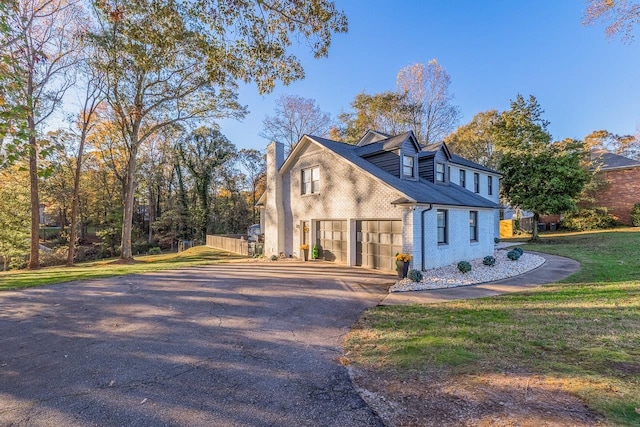 view of front of house featuring driveway, a chimney, a front lawn, and brick siding