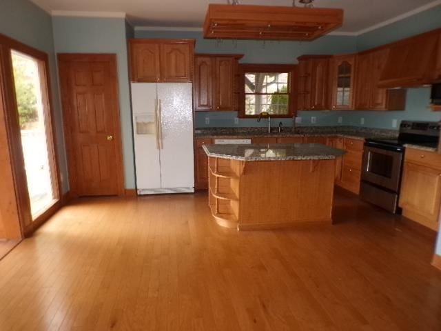 kitchen featuring light wood-style flooring, white refrigerator with ice dispenser, electric stove, ornamental molding, and a center island